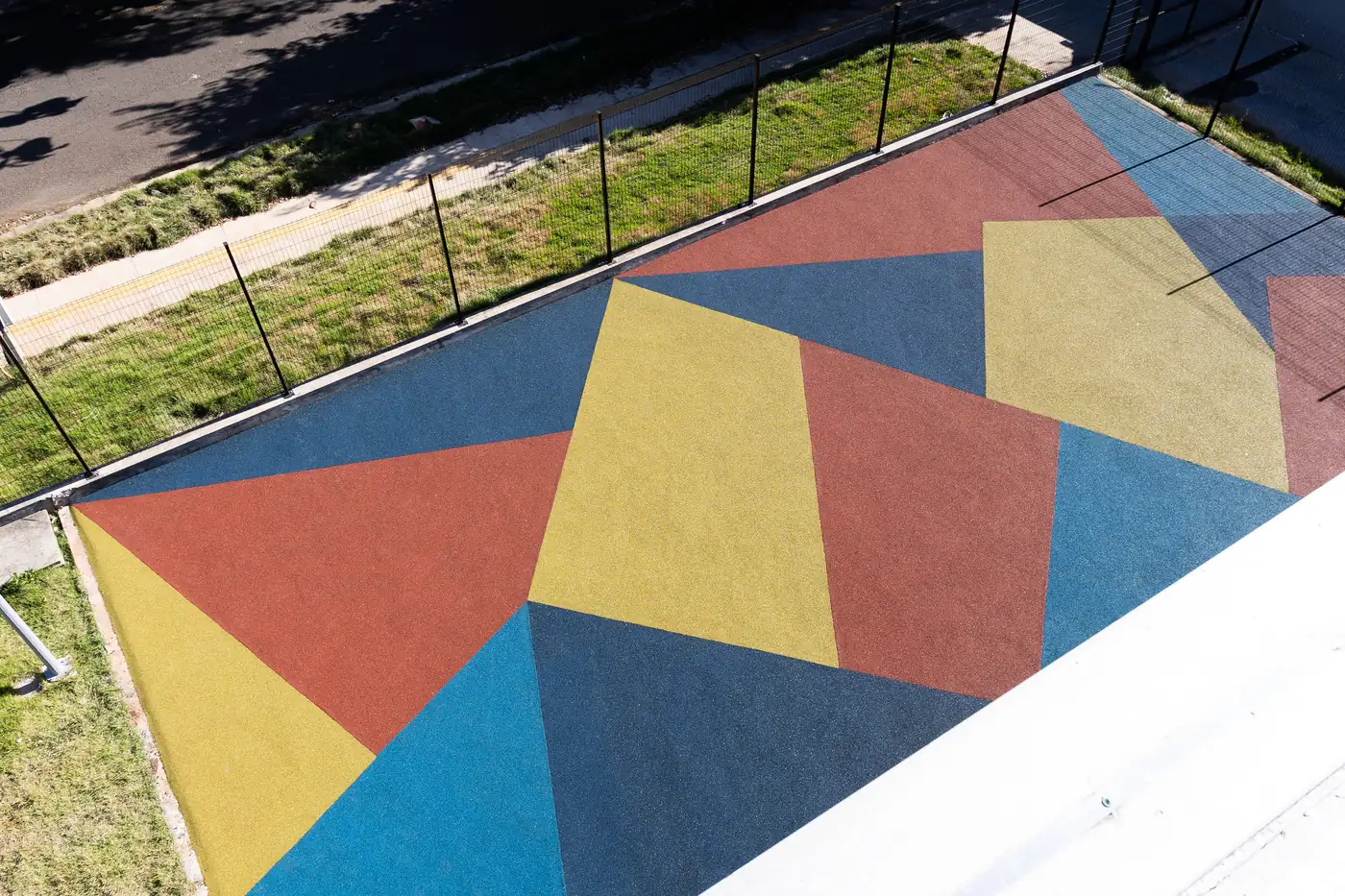 Formas geométricas grandes em borracha azul, vermelha e amarela no piso de uma escola
