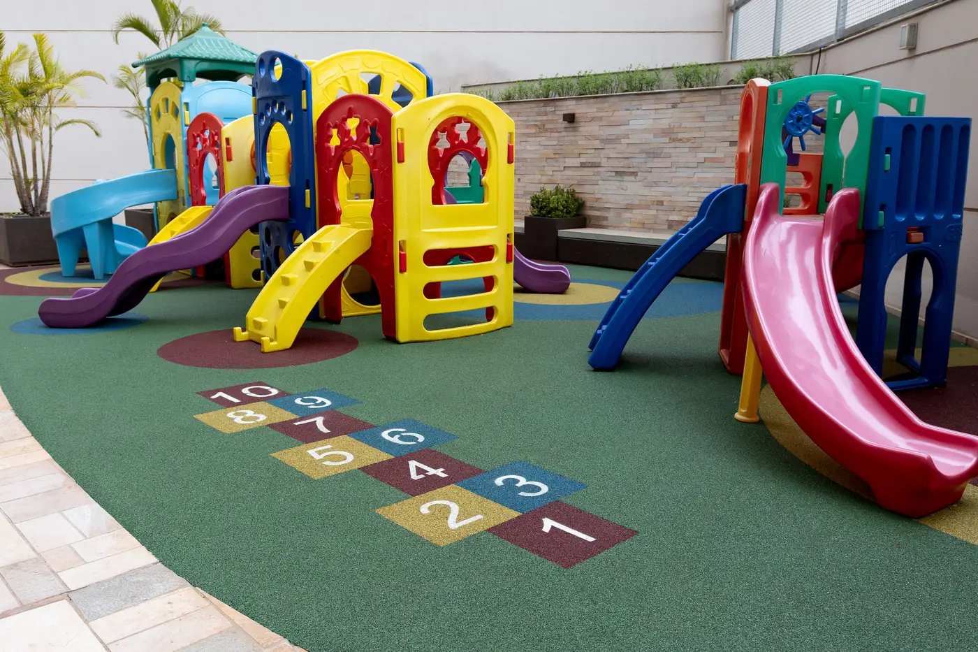 Playground de condomínio com piso monolítico SBR verde e amarelinha integrada no Maison Unique, Londrina/PR