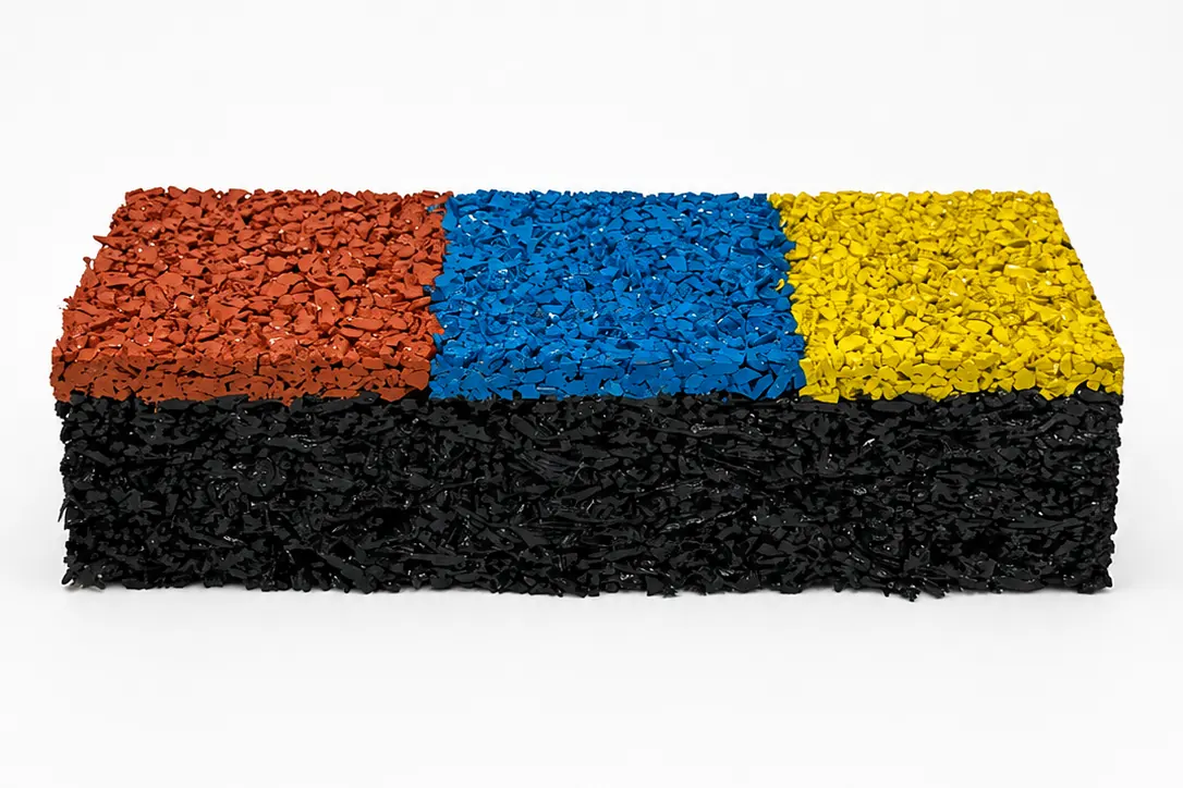 Corte de uma amostra do piso: base preta de borracha e camada superior de EPDM vermelho, azul e amarelo