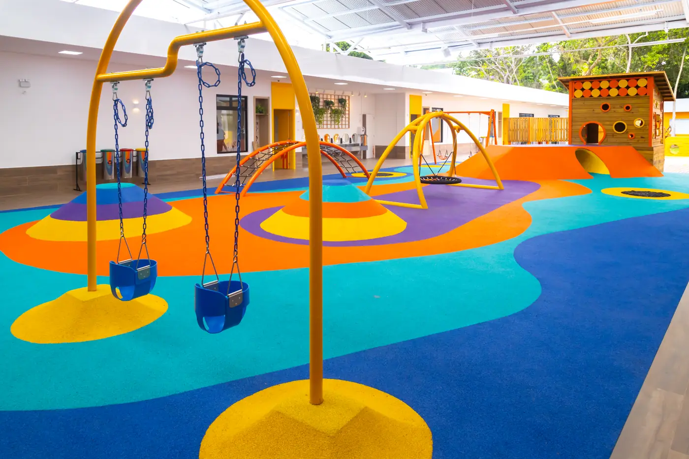 Balanços sobre piso monolítico EPDM azul, laranja e amarelo no Colégio Positivo Vila Olímpia, Florianópolis/SC