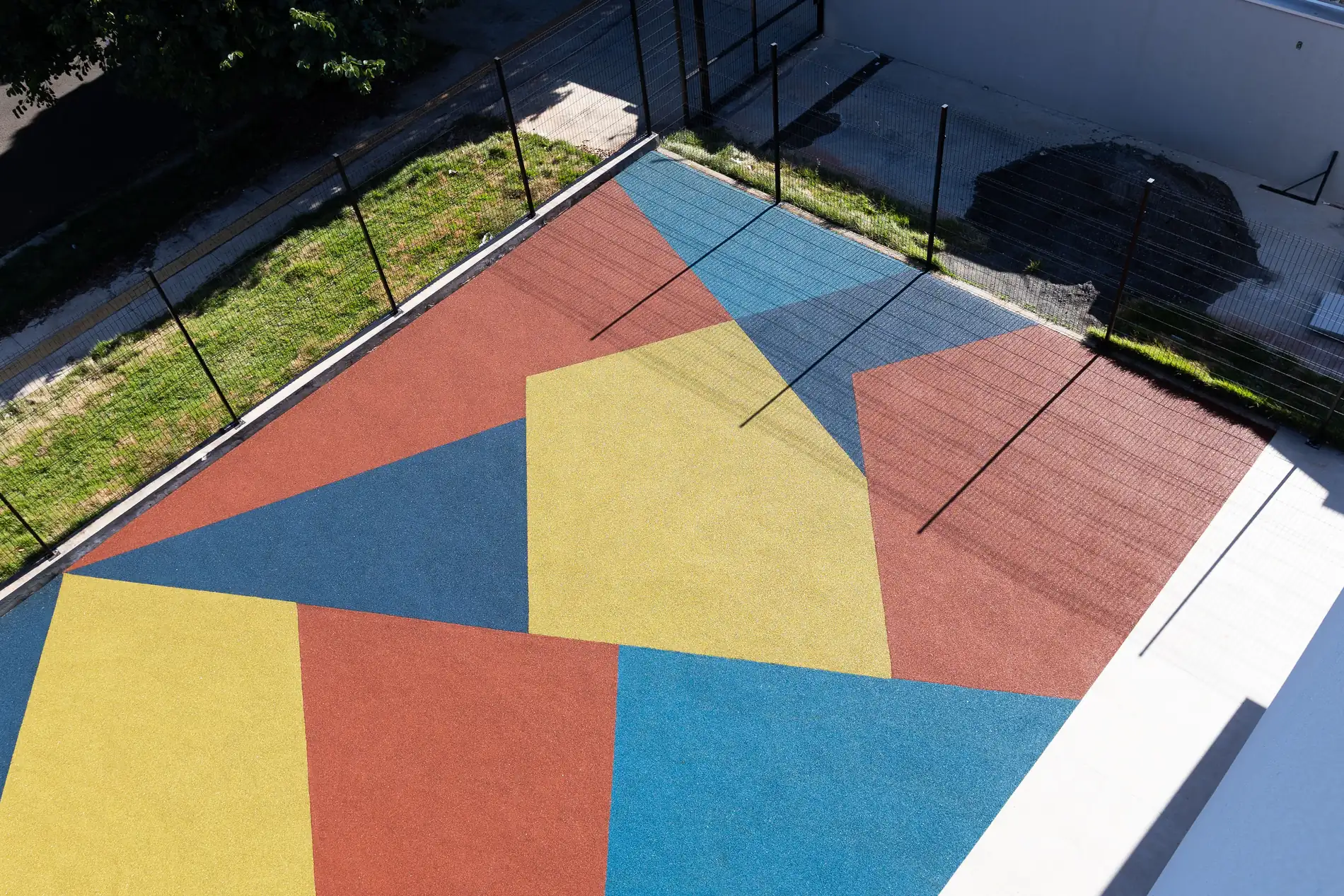 Pátio com piso monolítico SBR em formas geométricas azul, vermelho e amarelo na Escola Municipal Jardim Santa Alice, Maringá/PR